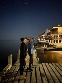 two people standing on a dock at night