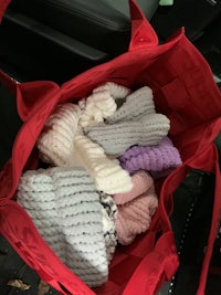 a red bag filled with knitted items in the back seat of a car