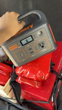 a person holding a portable generator in the back of a vehicle