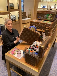 a woman standing in front of a louis vuitton trunk