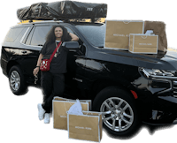 a woman standing next to a black suv with bags on top