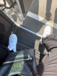 a person's feet sitting on the back seat of a bus