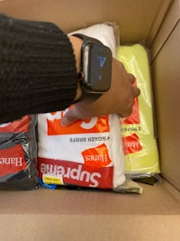 a person holding a supreme watch in a box